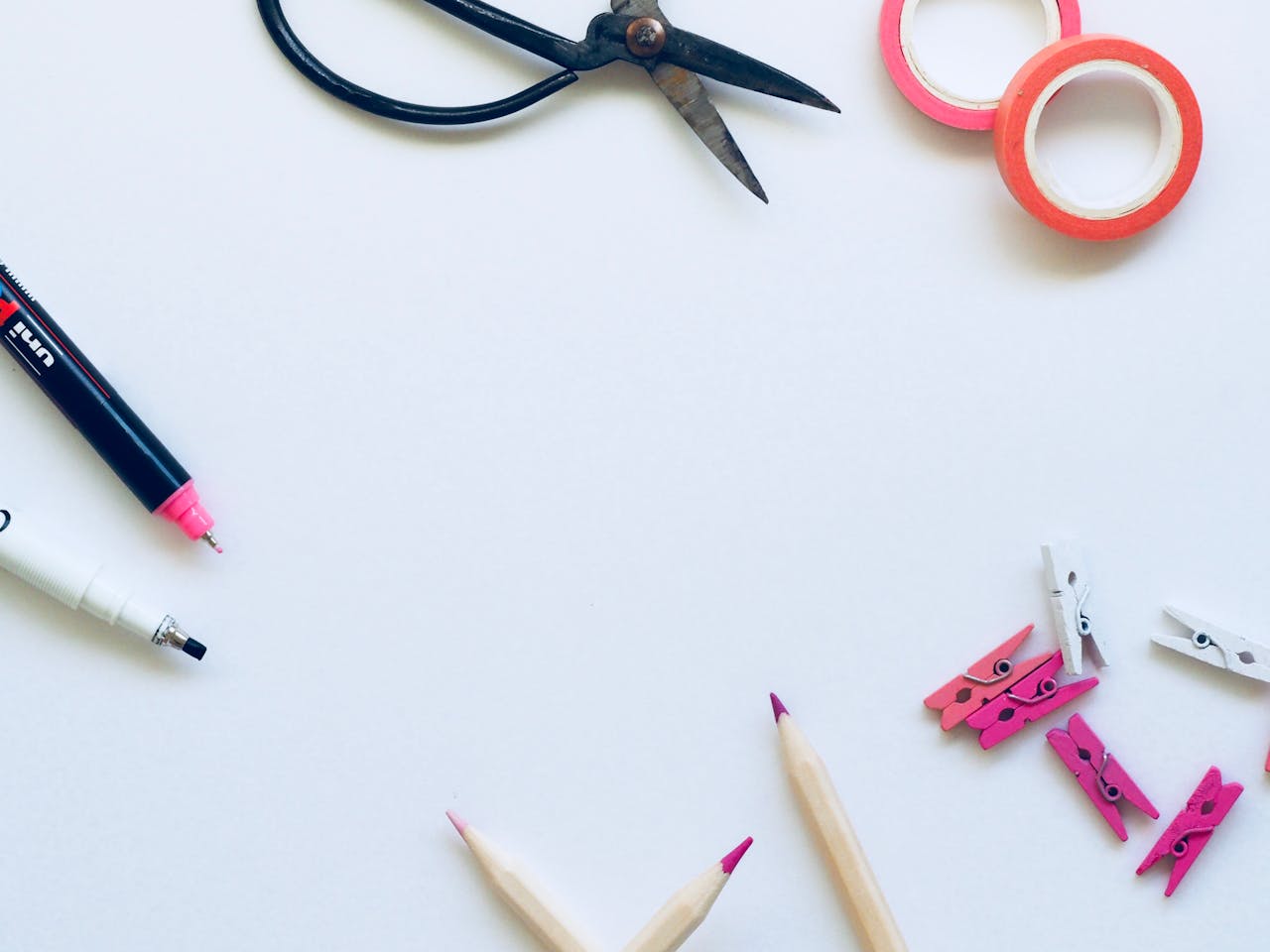 Art supplies including scissors, markpens, washi tape, and pegs on a white background, perfect for crafts.